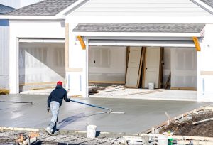 man,working,on,smoothing,concrete,driveway,for,the,new,home